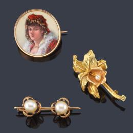 Lote 2022: Lote con tres broches, uno con motivo floral y perlita, otro con dos perlas y el tercero con figura femenina en esmalte, realizados en oro amarillo de 18K.
