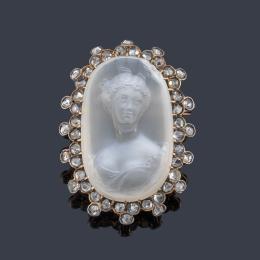 Lote 2047: Broche-camafeo con busto femenino clásico tallado en piedra luna con orla de diamantes talla rosa de aprox. 0,96 ct en total. Ppios S.XX.