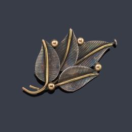 Lote 2034: Broche con diseño de vegetal de hojas realizado en montura de plata y detalles en oro amarillo de 18K.