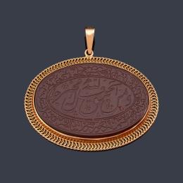Lote 2425: Colgante ovalado con motivo central con letras árabes realizado sobre resina marrón y enmarcado en montura de oro rosa de 18K.