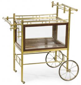 Lote 1210: Carro camarera art decó, con estructura de metal tubulado dorado, con compartimento en madera, acristalado y tapa abatible
Años 30
