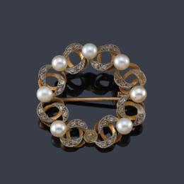Lote 2053: Broche circular con diseño ondulado con perlitas y diamantes talla rosa, en montura de oro amarillo de 18K y vista en platino. Circa 1920.