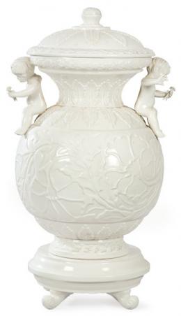 Lote 1120: Tibor en cerámica esmaltada en blanco de bassano con asas en forma de puttis con flores. 
Italia, años 80