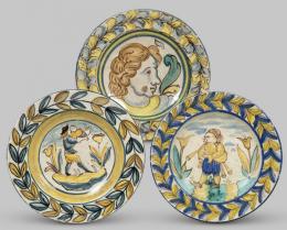 Lote 1077: Conjunto de tres platos de cerámica pintada y esmaltada de Triana, con personajes en el asiento y cenefas de hojas en el alero.
Sevilla, S. XVIII-XIX