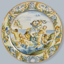 Lote 1075: Gran plato en cerámica pintada y esmaltada de Castelli, con escena del "Triunfo de Anfítrite" y amorcillos con guirnaldas en el alero. Italia, principios S. XX