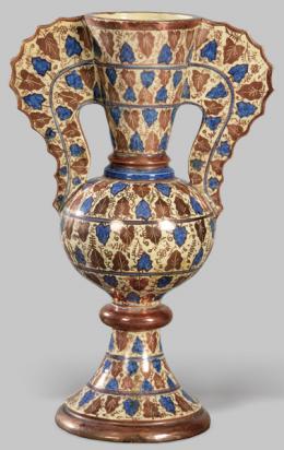 Lote 1272: Jarrón en cerámica esmaltada de reflejo metálico siguiendo modelos de la Alhambra con decoración de hojas de vid en color cobre y azul.
Granada, finales S. XIX