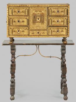 Lote 1276: Bargueño sin tapa, presenta tres cajones a cada lado de una portada grande inscrita en un rectángulo, sobre un cajón más pequeño. Realizado en madera de nogal, tallada y dorada, con columnillas de hueso. España, finales S. XVII