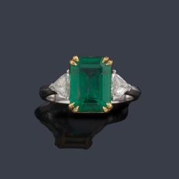 Lote 2158: Anillo con esmeralda central de aprox. 2,99 ct con dos diamantes talla triángulo de aprox. 0,43 ct en total.