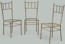 Lote 1279: Conjunto de tres sillas con respaldo y asiento calado, y patas unidas por chambranas, en hierro pintado de dorado imitando bambú.
Años 50