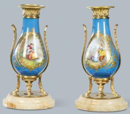 Lote 1269
Pareja de jarrones de porcelana azul celeste tipo Sevres con montura de bronce, sobre base de mármol. Con decoración de escenas galantes en cartelas.