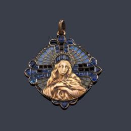 Lote 2016: Medalla devocional con La Imagen de La Virgen realizada en oro amarillo enmarcada sobre un tipo de vidriera con esmalte y zafiros calibrados. Circa 1905.
