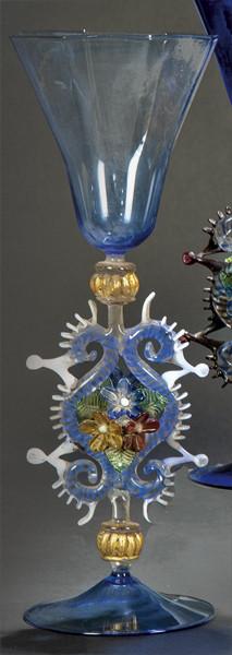 Lote 1091
Copa de cristal de Murano azul con depósito poligonal y vástago con eses adosadas, crestería y flores.