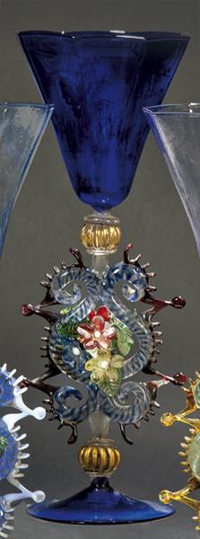 Lote 1092
Copa de cristal de Murano azul cobalto con depósito poligonal y vástago con eses adosadas, crestería y flores.