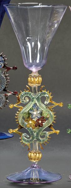 Lote 1093
Copa de cristal de Murano color lila con depósito poligonal y vástago con eses adosadas, crestería y flores.