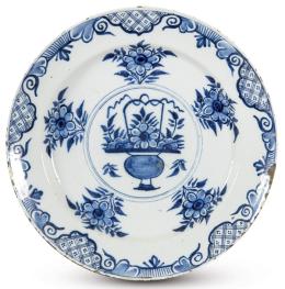 Lote 1108: Plato en cerámica esmaltada en azul cobalto y blanco, en el centro se representa un jarrón con flores insertado en un círculo con líneas concéntricas y una cenefa con motivos geométricos y vegetales en el alero. Faltas
Holanda, S. XVIII