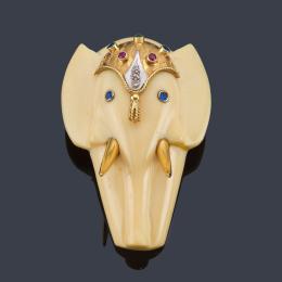 Lote 2150: Colgante con cabeza de elefante realizada en marfil con detalles en oro amarillo de 18K, con rubíes, zafiros y diamantes. Años '70.