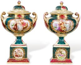 Lote 1042: Pareja de copas bajas con asas en porcelana esmaltada de Viena, sobre basamentos, con escenas clásicas en cartelas. 
Austria, principios S. XX