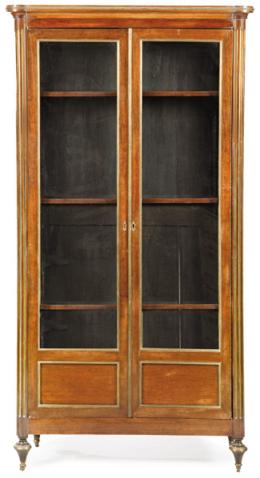 Lote 1256: Mueble libreria directorio en madera de caoba con aplicaciones de bronce. Tiene dos puertas abatibles acristaladas que revelan un interior con baldas regulables en altura. Francia, principios S.XIX