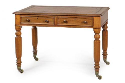  Escritorio Guillermo IV en madera de nogal con tapa en piel gofrada y patas torneadas rematadas en ruedas. Inglaterra, mediados S. XIX