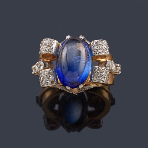 Lote 2090
Anillo retro con zafiro en cabujón de aprox. 10,53 ct con cuatro roleos decorados con diamantes en montura de oro amarillo de 18K.