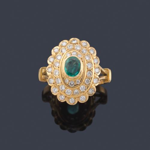  Anillo con esmeralda talla oval y tres orlas de brillantes en montura de oro amarillo de 18K.