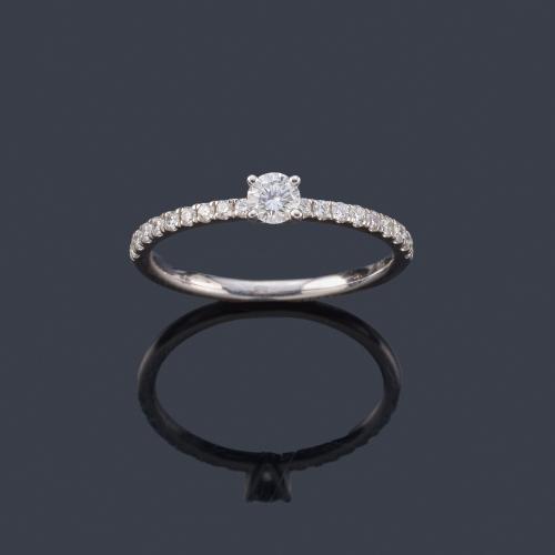 Lote 2495
Solitario con brillante de aprox. 0,20 ct con banda de brillantes en montura de oro blanco de 18K.