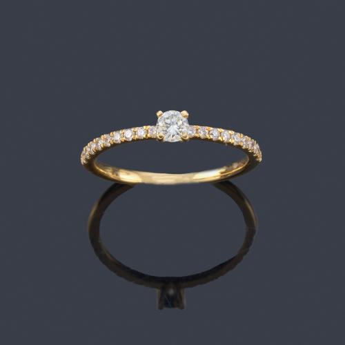 Lote 2496
Anillo con brillante central de aprox. 0,20 ct con bandas de brillantes en ambos lados.