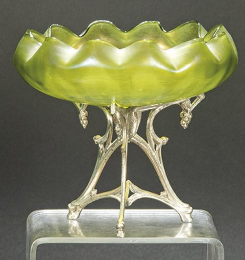  Josef Rindskopf & Söhne, Bohemia h. 1890
Centro de mesa en cristal verde iridiscente con boca rizada y patas de metal plateado con racimos de uva.