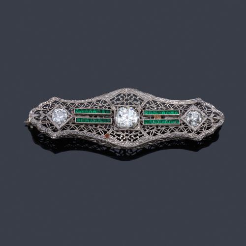 Lote 2037
Broche-barrita con tres diamantes talla cojín antigua de aprox. 1,35 ct en total y esmeraldas calibradas.
