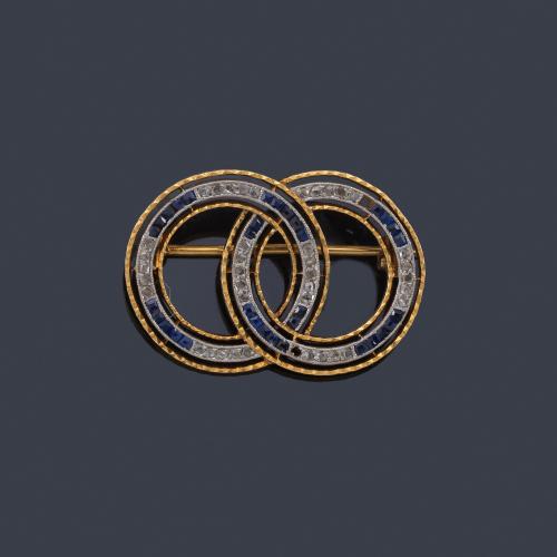  Broche con motivo de doble círculo con diamantes talla rosa y zafiros calibrados, en montura de oro amarillo de 18K y vista en platino.
