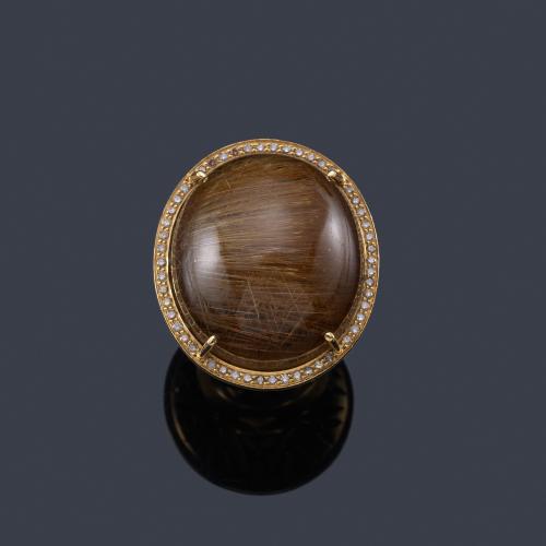 Lote 2426
Anillo con gran cuarzo rutilado en cabujón con orla de brillantes en montura de oro amarillo de 18K.