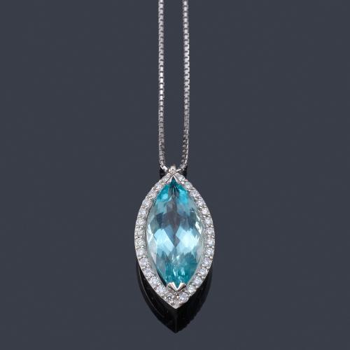Lote 2470
Colgante con aguamarina talla marquís facetada de aprox. 7,80 ct con orla de brillantes, en montura de oro blanco de 18K con cadena.