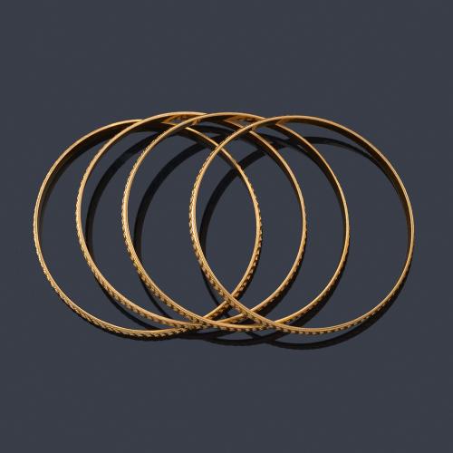  Cuatro pulseras rígidas con motivos cincelados en oro amarillo de 18K.
