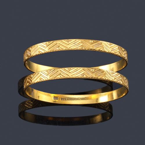  Dos pulseras rígidas con motivos geométricos cincelados en oro amarillo de 22K.