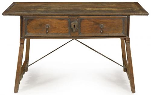  Mesa bufete en madera de nogal, con gran cajón en el frente compartimentado en su interior, sobre patas unidas por chambranas y fiadores de hierro.
España, S. XVII