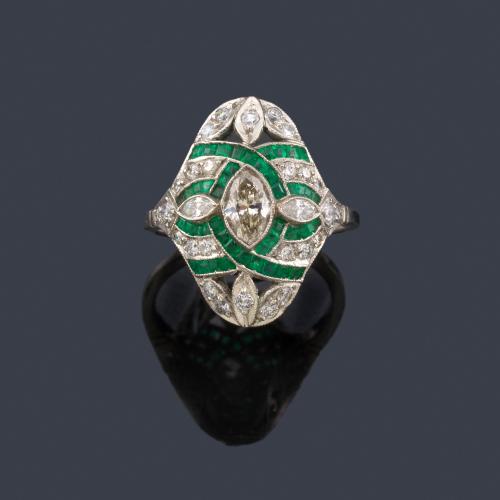  Anillo lanzadera con diamante talla marquís de aprox. 0,56 ct con bandas curvadas de esmeraldas calibradas y brillantes de aprox. 0,46 ct en total.