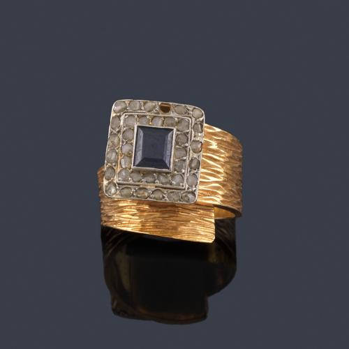  Anillo con centro de zafiro y doble orla de diamantes talla rosa en montura de oro amarillo de 18K en textura rallada.