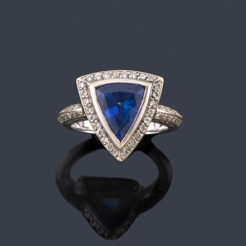  Anillo con tanzanita talla triángulo con orla y brazos de brillantes en montura de oro blanco de 18K.
