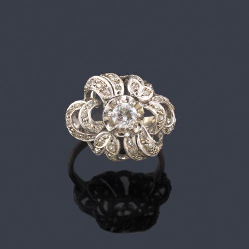 Lote 2492
Anillo con diamante talla antigua central de aprox. 0,30 sobre diseño de volutas enriquecidas con diamantes talla rosas.