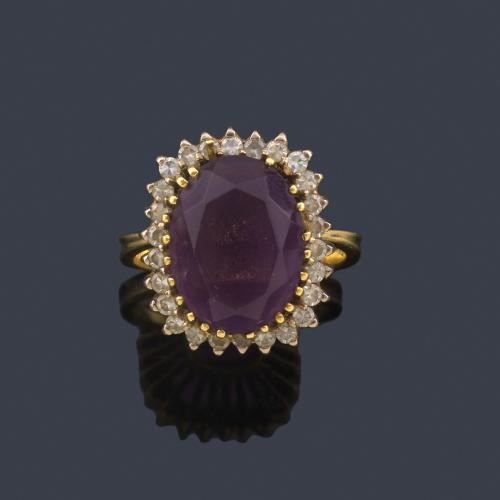  Anillo con amatista talla oval con orla de brillantes en montura de oro amarillo de 18K.