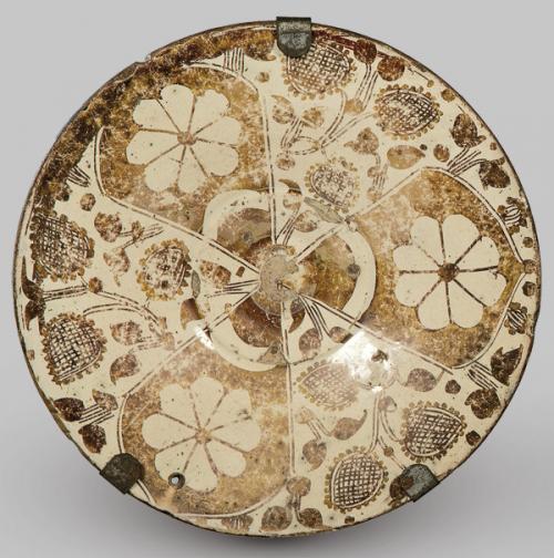  Plato de perfil cóncavo, troncocónico muy abierto, con borde ligeramente exvasado. Realizado en loza estannífera con decoración de reflejo metálico dorado.