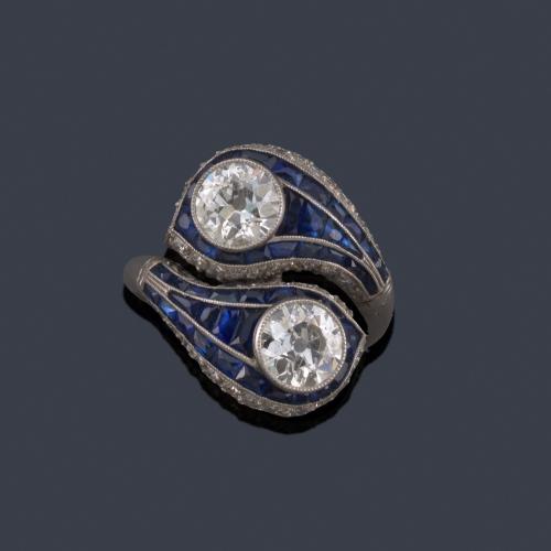 Lote 2047
Anillo 'tu y yo' con pareja de diamantes talla antigua de aprox. 1,00 ct cada uno con orla de zafiros calibrados.