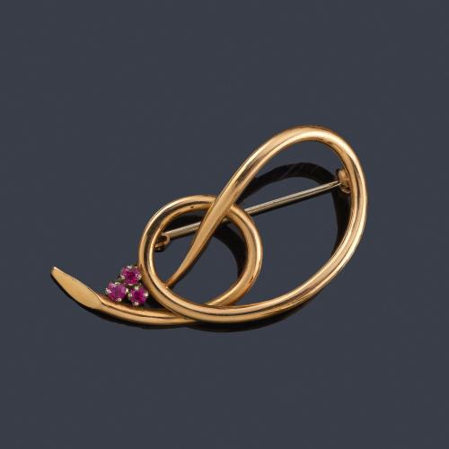  Broche con diseño circular con tres rubíes sintéticos, en montura de oro amarillo de 18K.