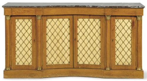  Aparador siguiendo modelos regencia ingleses en madera de palosanto, de tres cuerpos con el central cóncavo separados por columnas de orden corintio con bases y capiteles de bronce. Frente de las puertas con celosía de latón y sobre de mármol negro. S. XX