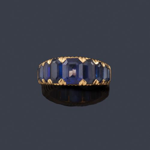 Anillo con banda de zafiros sintéticos talla rectangular en disminución sobre montura gallonada de oro amarillo de 18K.