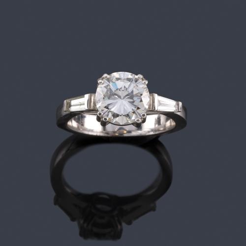  Solitario con brillante central de aprox. 1,95 ct con dos diamantes talla trapecio en montura de oro blanco de 18K.