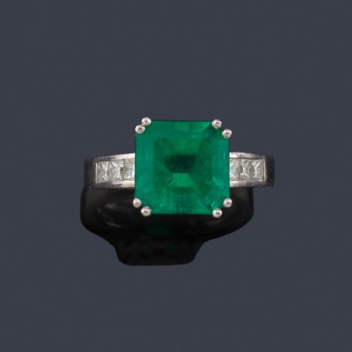  Anillo con esmeralda central de aprox. 3,50 ct con diamantes talla princesa en ambos lados.