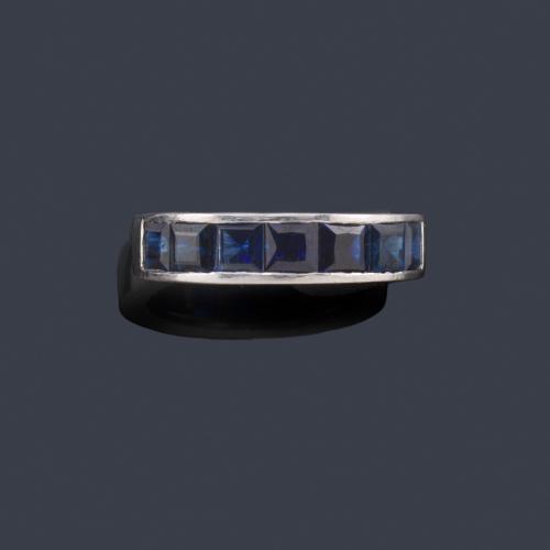  Anillo con banda de zafiros calibrados en montura de oro blanco de 18K.