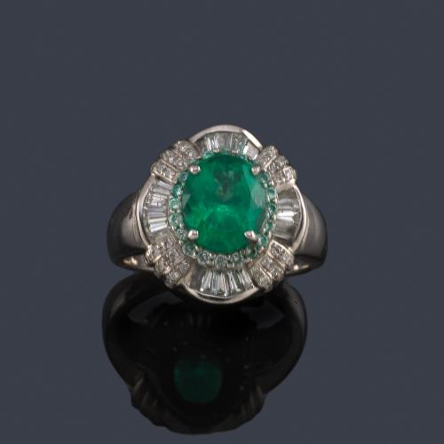  Anillo con esmeralda talla oval de aprox. 1,96 ct con orla de diamantes talla brillante y trapecio de aprox. 2,10 ct en total.