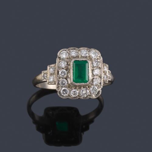  Anillo con esmeralda rectangular central y orla de brillantes en montura de platino.